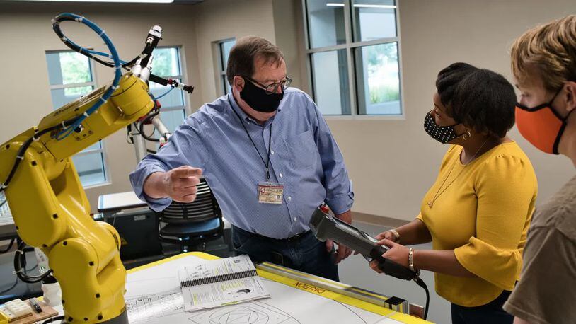 Wesley Evans, program coordinator for the Sinclair Community College Electronics Engineering Technology Department, demonstrates robotics to students inside the advanced manufacturing lab at the Courseview Campus in Mason. FILE