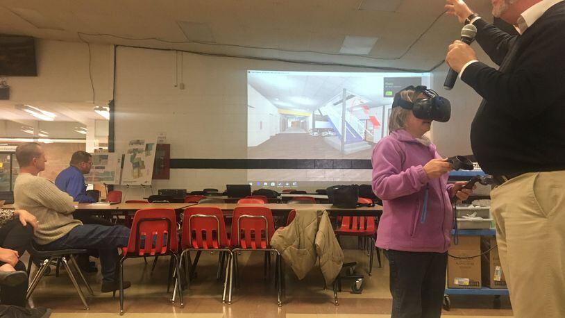SHP Leading Design Project Manager John Predovich speaks as Greenon resident Sabrina Akers wears virtual reality goggles and takes a tour of a high school.