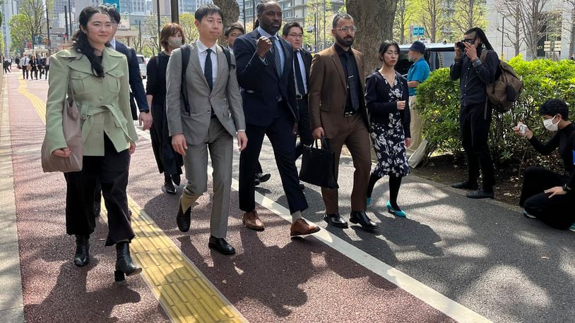 Motoki Taniguchi, second left in front, one of the lawyers, Maurice Shelton, front center, a plaintiff and Syed Zain, second right in front, a plaintiff arrive in front of the Tokyo District Courthouse in Tokyo as the plaintiffs enter for the opening session Monday, April 15, 2024. A civil lawsuit accusing Japanese police of racial profiling opened Monday with emotional testimony from plaintiffs who said they were constantly stopped and questioned without good reason. (AP Photo/Yuri Kageyama)