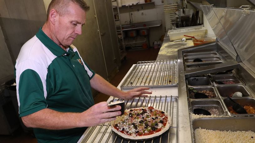 Kenneth Couch, the general manager of Slice of Heaven Pizzeria, makes a pizza. BILL LACKEY/STAFF