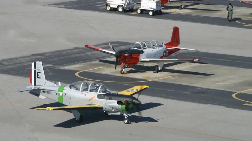 A unique T-34 "Turbo Mentor" passes in front of several other T-34's painted in orange and white colors. The aircraft's grey and yellow paint scheme, with Marine markings, were part of the Centennial of Naval Aviation's 2011 celebration. (Photo by: 2nd Lt. Molly LeBlanc)