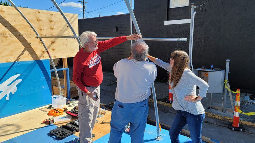 Dale Grimm and April Lowry confer with Marshall Gorby as they work to put up the Brat and Beer Hanger at Heritage of Flight. Photo by Mike Lowry.