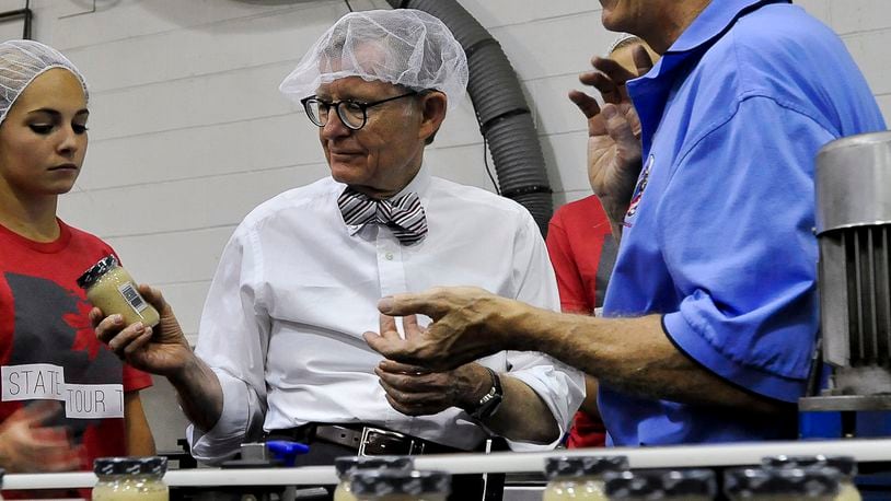 Former Ohio State President, Dr. Gordon Gee looks over a jar of Woeber’s horseradish as Dan Woeber, right, gives him a tour of the company’s Springfield plant during a previous visit to Clark County. Staff photo by Bill Lackey