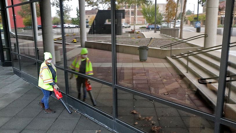 Joan Hawkins, a member of the City of Springfield Maintenance Department, blows the leaves off the City Hall Plaza Thursday. The city plans to make several improvements to the downtown plaza, which is reflected in the windows of City Hall. BILL LACKEY/STAFF
