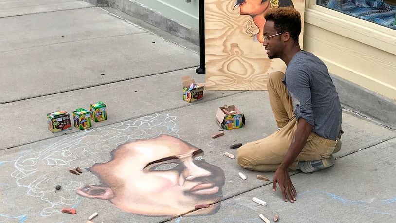 Dayton-based chalk artist Boy Blue uses chalk to create a piece of art along North Fountain Avenue in Springfield on Friday afternoon. Boy Blue will also be creating another piece of chalk art at Saturday’s Chalktoberfest being held in downtown Springfield. Michael Cooper/Staff