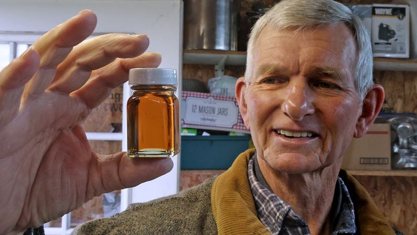 Ben Hamilton talks about how the relationship between the color of maple syrup and the taste in his backyard sugar shack Thursday. BILL LACKEY/STAFF