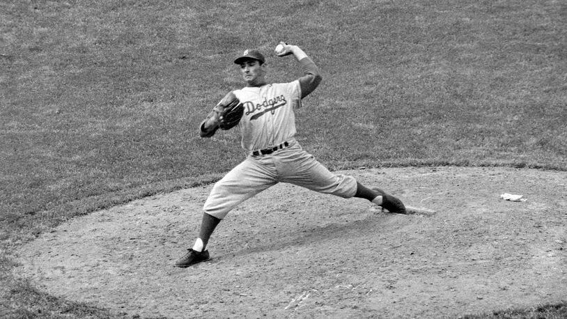 Brooklyn Dodgers southpaw Sandy Koufax, who ended his bonus tenure the day before, pitches against the Chicago Cubs in the eighth inning of a baseball game, Thursday, May 16, 1957, in Chicago. On Monday, March 14, 2022, the Los Angeles Dodgers announced that Koufax is joining fellow Hall of Famer Jackie Robinson with a bronze statue of his own at Dodger Stadium, with an unveiling planned for June 18, 2022, before the team hosts Cleveland. (AP Photo/Harry Hall, File)