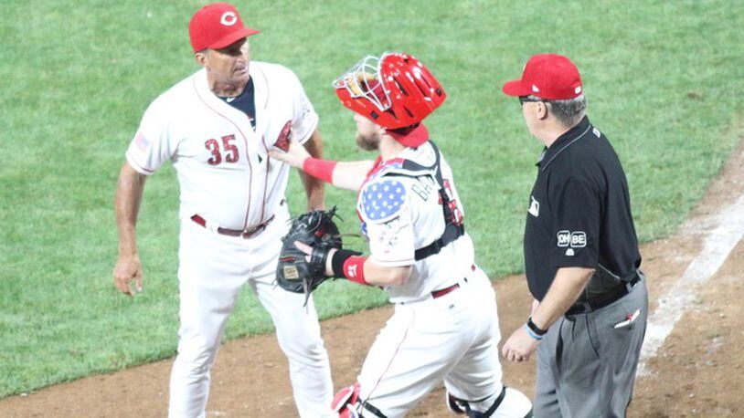 Reds catcher Tucker Barnhart holds back interim manager Jim Riggleman as he argues with Eric Cooper in the 12th inning of a game against the Chicago White Sox on Tuesday, July 3, 2018, at Great American Ball Park in Cincinnati. David Jablonski/Staff