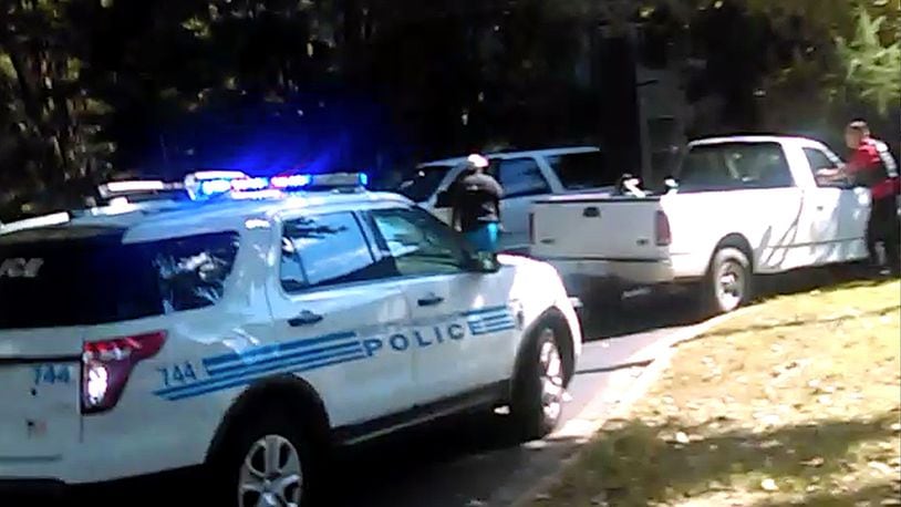 In this image taken from video recorded by Rakeyia Scott on Tuesday, Sept. 20, 2016, her husband, Keith Lamont Scott, center, stands amid Charlotte police cars and other vehicles moments before he is shot by a police officer in Charlotte, N.C. In the video of the deadly encounter, Rakeyia Scott repeatedly tells officers her husband, who is black, is not armed and pleads with them not to shoot him as they shout at him to drop a gun. The video does not show clearly whether Scott had a gun. (Rakeyia Scott/Curry Law Firm via AP)