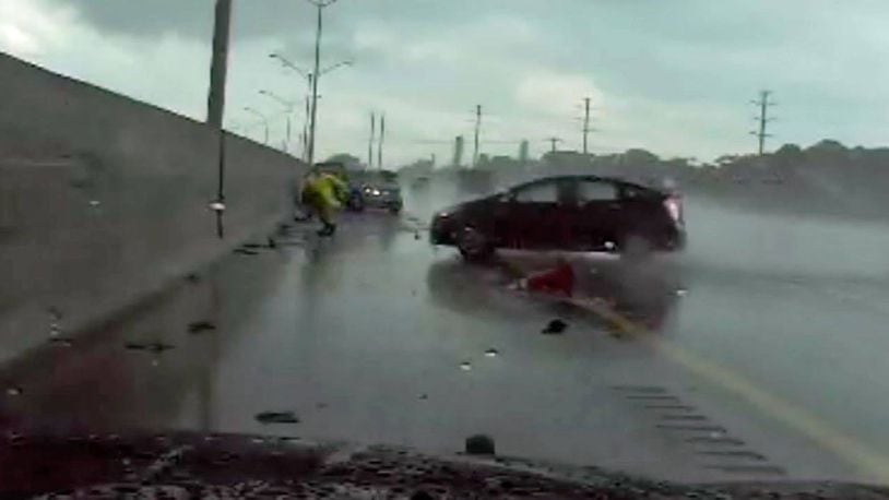 A state trooper sprints to avoid a hydroplaning car Monday in South Florida.