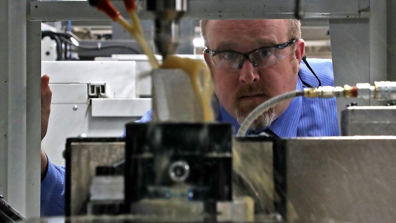 Jason Chilman, an instructor in the engineering department at Clark State Community College, watches the 5 axis milling machine at work in the manufacturing lab at the Clark State Community College. BILL LACKEY/STAFF