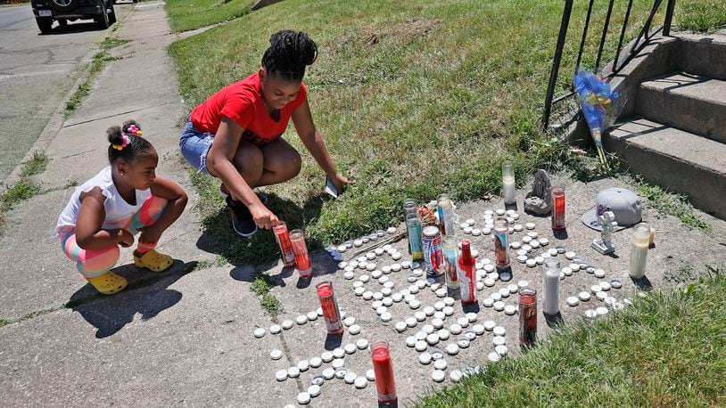 Corah Belle, right, and Chandlor Robinson, cousins of Eric Cole, light some of the candles that had gone out on the memorial along South Center Street near where Cole was shot and than run over by a responding police officer Sunday night. BILL LACKEY/STAFF