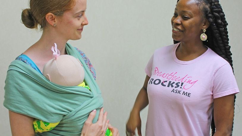 Clark County WIC program employees Erin Sanford and Safiyyah Truss demonstrate how to properly put on an infant wrap as part of Breastfeeding Awareness Month activities. JEFF GUERINI/STAFF