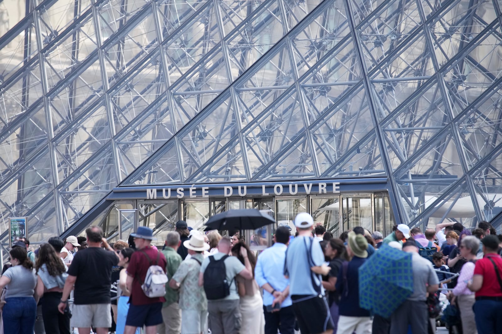 Tourists wait outside the Louvre museum which failed to open on time Monday, June 16, 2025 in Paris. (AP Photo/Christophe Ena)