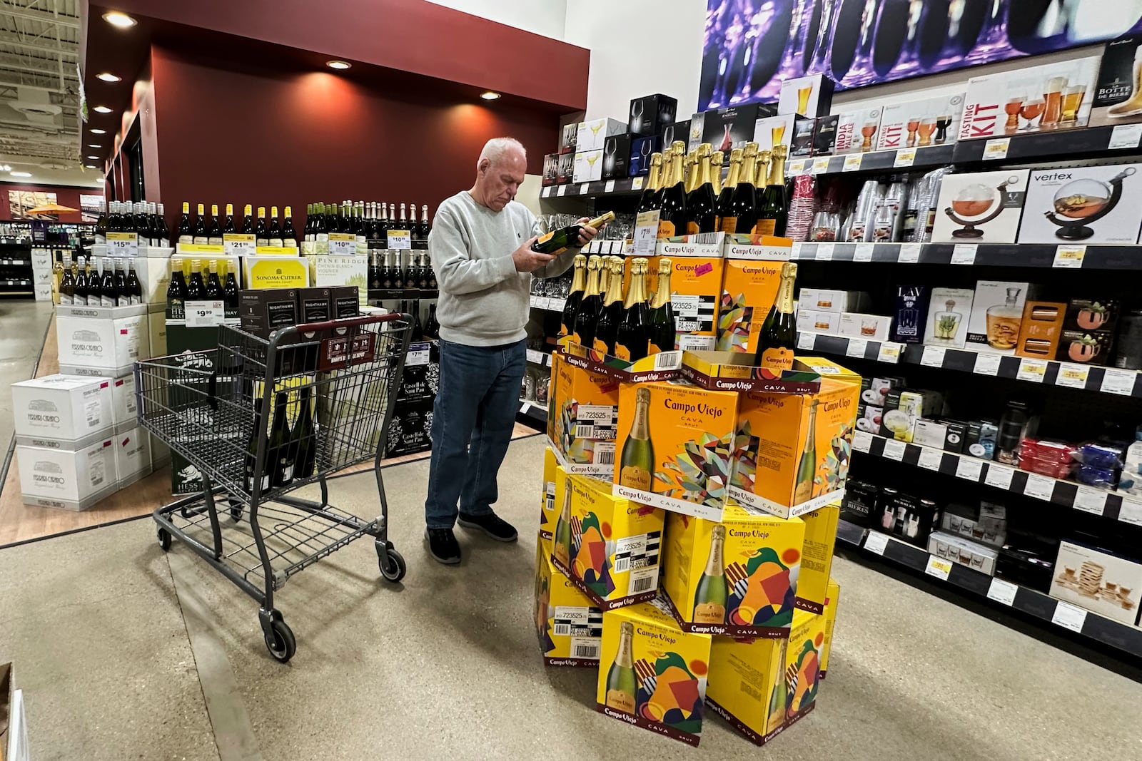 A shopper checks a bottle of Spain champagne at a liquor store in Niles, Ill., Thursday, April 3, 2025. (AP Photo/Nam Y. Huh)