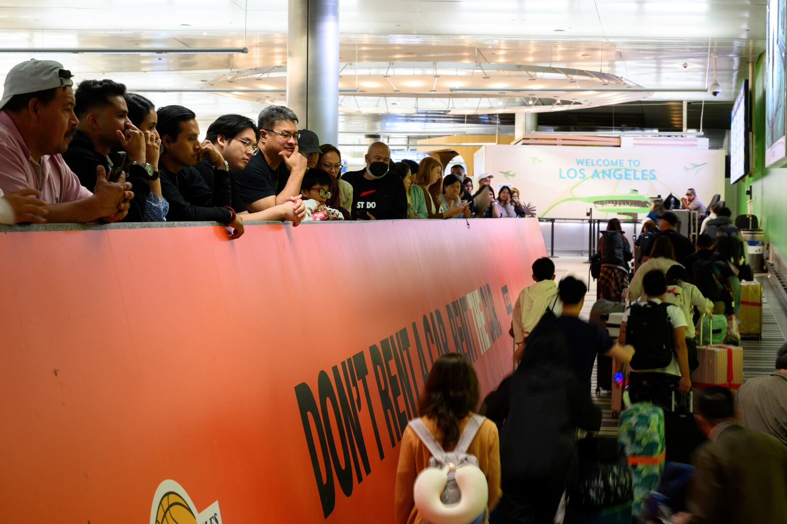 Travelers push their luggage through the international arrivals area at the Los Angeles International Airport in Los Angeles, Saturday, June 8, 2025. (AP Photo/William Liang)