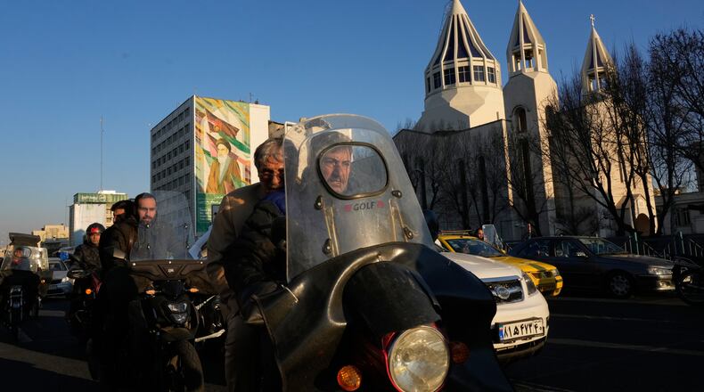 Commuters drive past Saint Sarkis church and a mural of the late Iranian revolutionary founder Ayatollah Khomeini in downtown Tehran, Iran, Wednesday, Feb. 25, 2026. (AP Photo/Vahid Salemi)