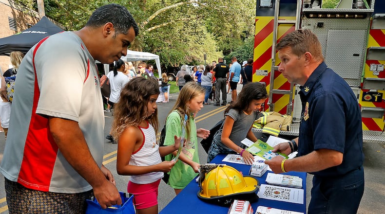 The Springfield Fire Division's Battalion Chief Jeremy Linn talks with a family about having an escape plan for their home in case of a fire on Aug. 1, 2023 during National Night Out in Veteran's Park. BILL LACKEY/STAFF