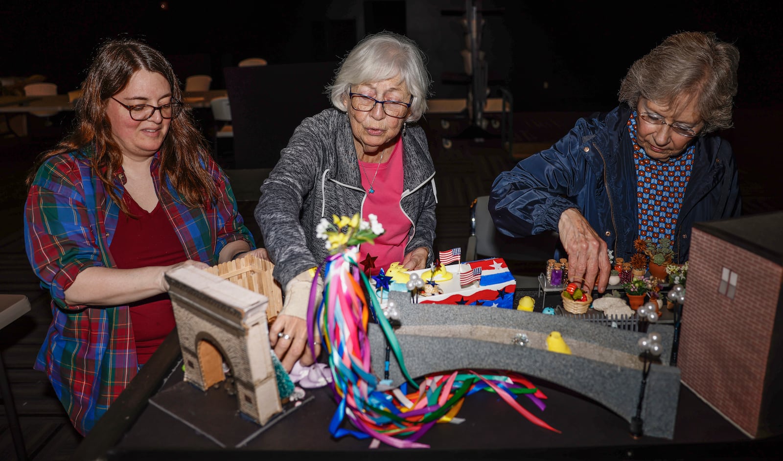 Natalie Fritz, left, archivist and outreach director for the Clark County Historical Society at the Heritage Center, and volunteers Jennie Zimmer, center, and Virginia Warren work to recreate a mixture of historic Clark County scenes on Wednesday, March 11, 2026, for their "Peeps in History" display at the Heritage Center in Springfield. Each year the group searches through the archives for a picture from Clark County's past. The group then recreates the scene using props and marshmallow Peeps as the people in the image. The Peeps will be on display in the Heritage Center until summer. JOSEPH COOKE/STAFF