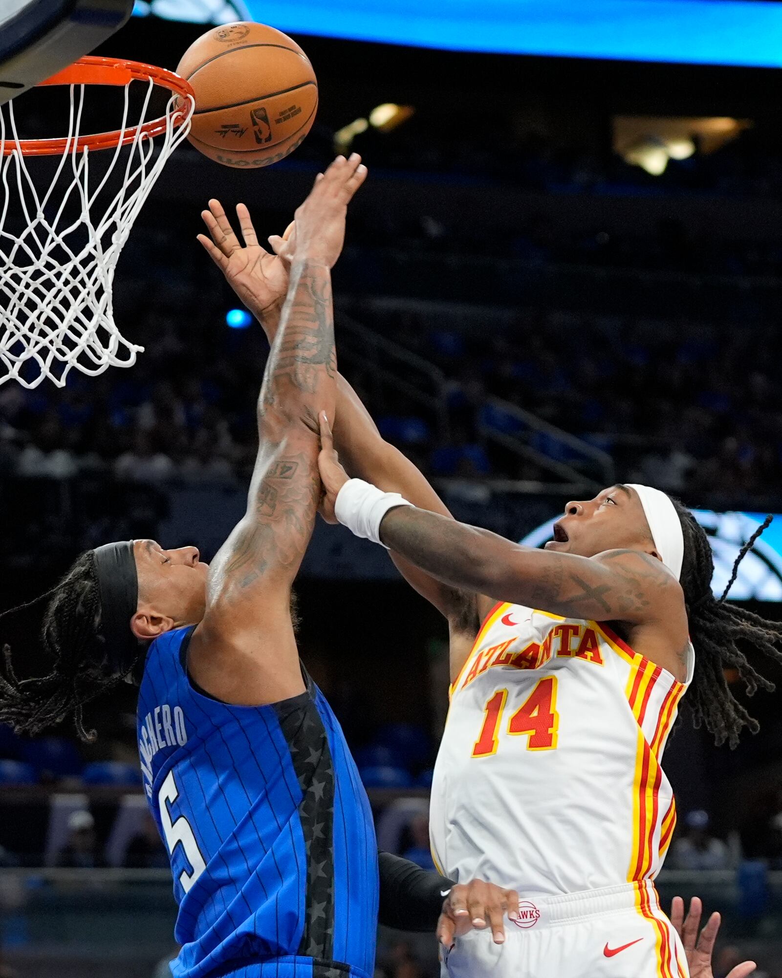 Orlando Magic forward Paolo Banchero (5) blocks a shot attempt by Atlanta Hawks guard Terance Mann (14) during the first half of an NBA play-in tournament basketball game, Tuesday, April 15, 2025, in Orlando, Fla. (AP Photo/John Raoux)