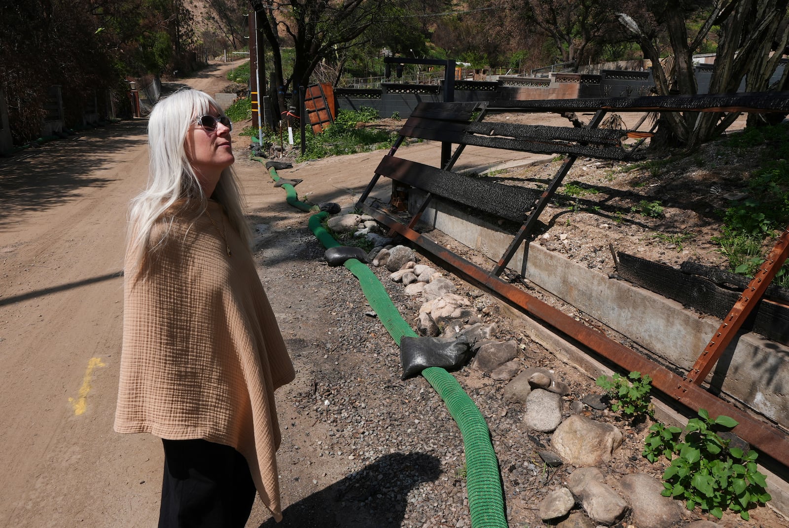 Kathryn Frazier looks at property, which was destroyed by the Eaton Fire in Altadena, Calif., on Tuesday, April 22, 2025. (AP Photo/Damian Dovarganes)