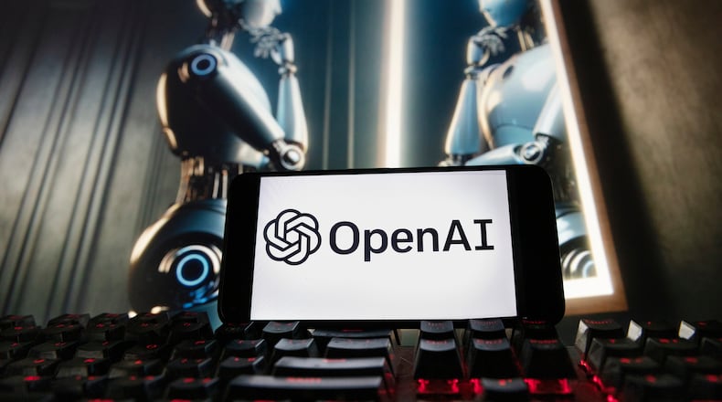 FILE - The OpenAI logo is displayed on a cellphone with an image on a computer monitor generated by ChatGPT's Dall-E text-to-image model, Dec. 8, 2023, in Boston. (AP Photo/Michael Dwyer, File)