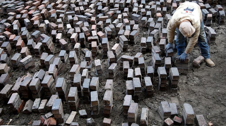 A crew from Natures Own Landscaping removes the bricks that make up North Market Place, the alley between the Clark County Heritage Center and COhatch the Market on Tuesday, Feb. 13, 2024. According to Roger Sherrock, CEO of the Clark County Historical Society, the bricks were put in place in 2002 when the Heritage Center building was renovated and museum opened. Sherrock said, over the past 22 years, many of the bricks had become broken and uneven. They will be replaced with new bricks that are level to prevent any tripping hazards. The Historical Society has also repaired the curbs and sidewalks along the pedestrian roadway over the past year. The area is used for farm markets and other community events. BILL LACKEY/STAFF