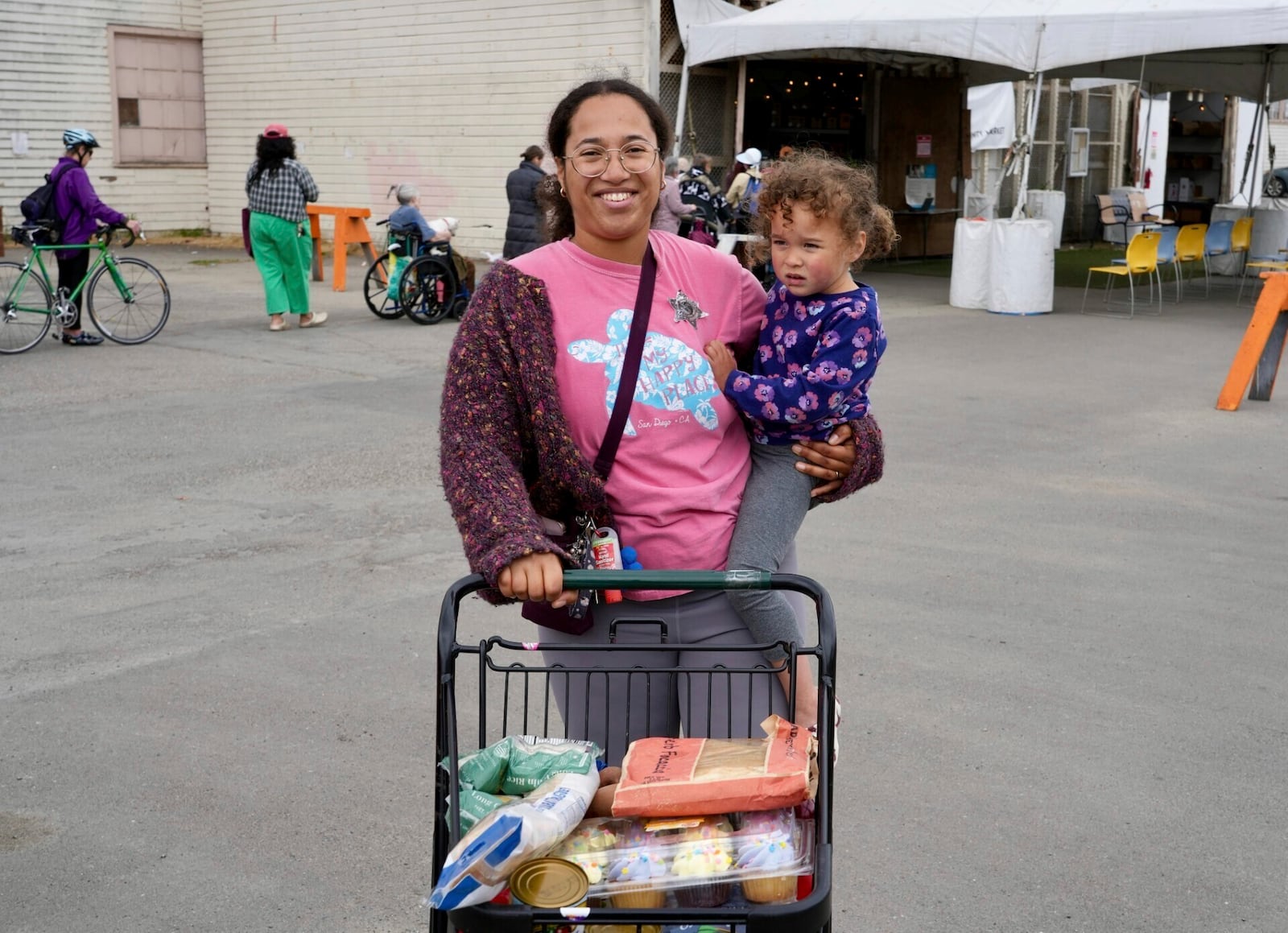 Alameda resident Christina Santamaria stands outside the Alameda Food Bank with groceries and her daughter in Alameda, Calif. on Friday, April 25, 2025. (AP Photo/Terry Chea)