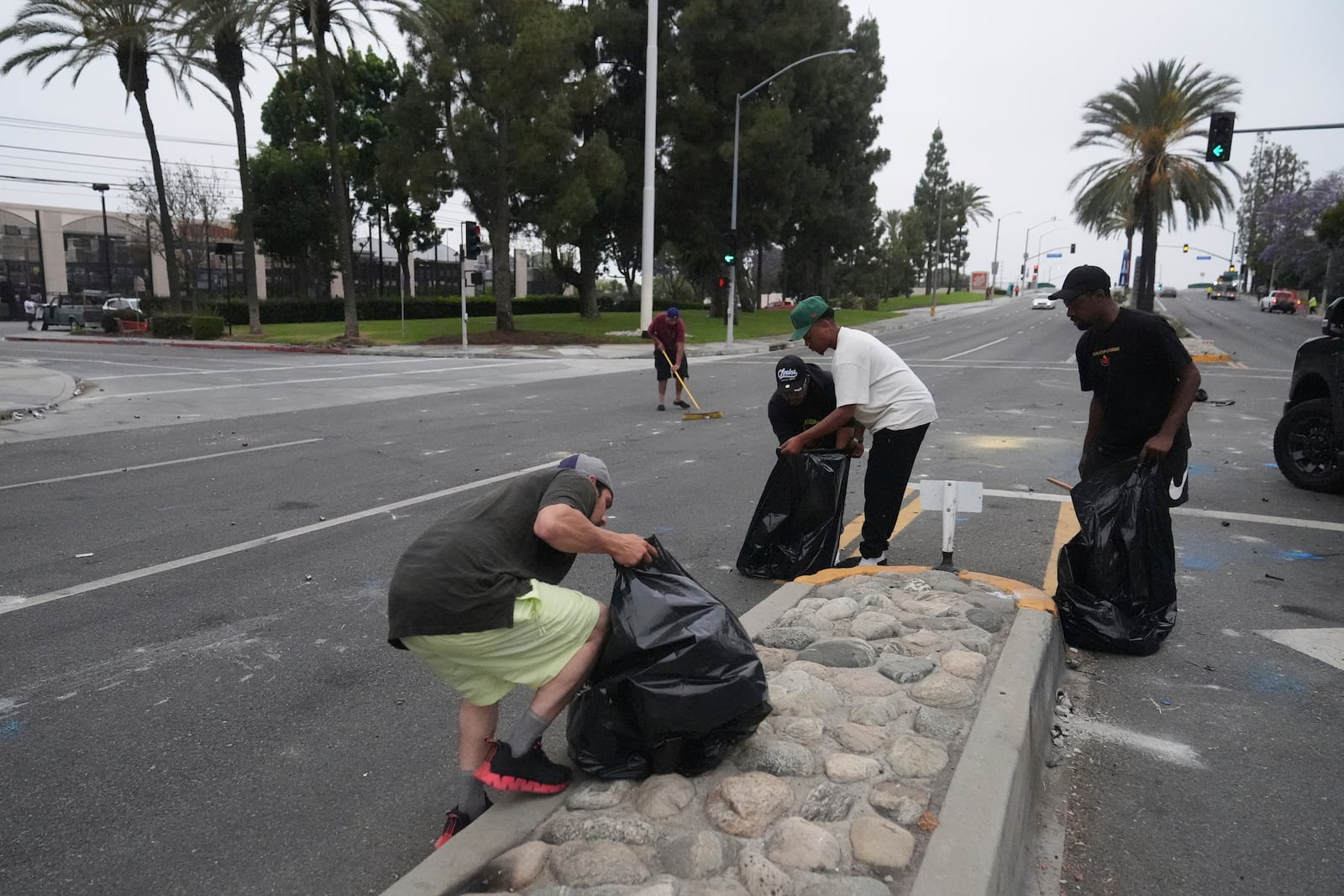 A local parishioners clean up the streets Sunday, June 8, 2025, in Paramount, Calif., following an immigration raid protest the night before. (AP Photo/Jae Hong)