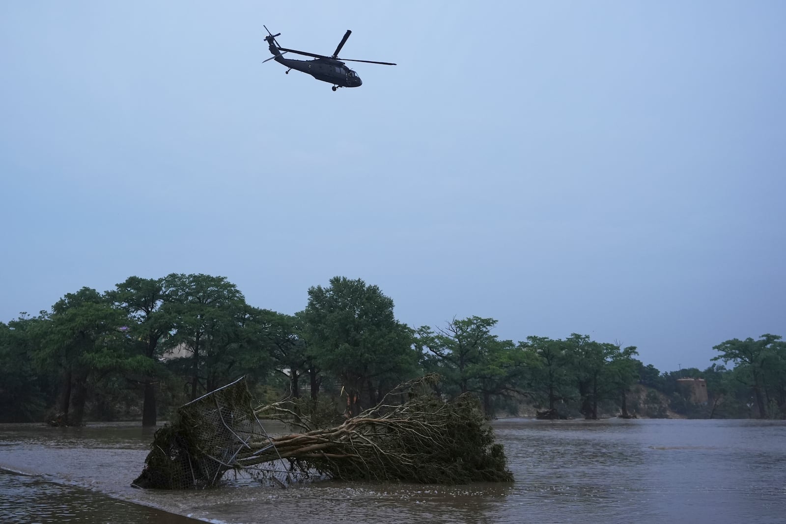 A helicopter flies over the Guadalupe River after a flash flood swept through the area, Friday, July 4, 2025, in Kerrville, Texas. (AP Photo/Eric Gay)