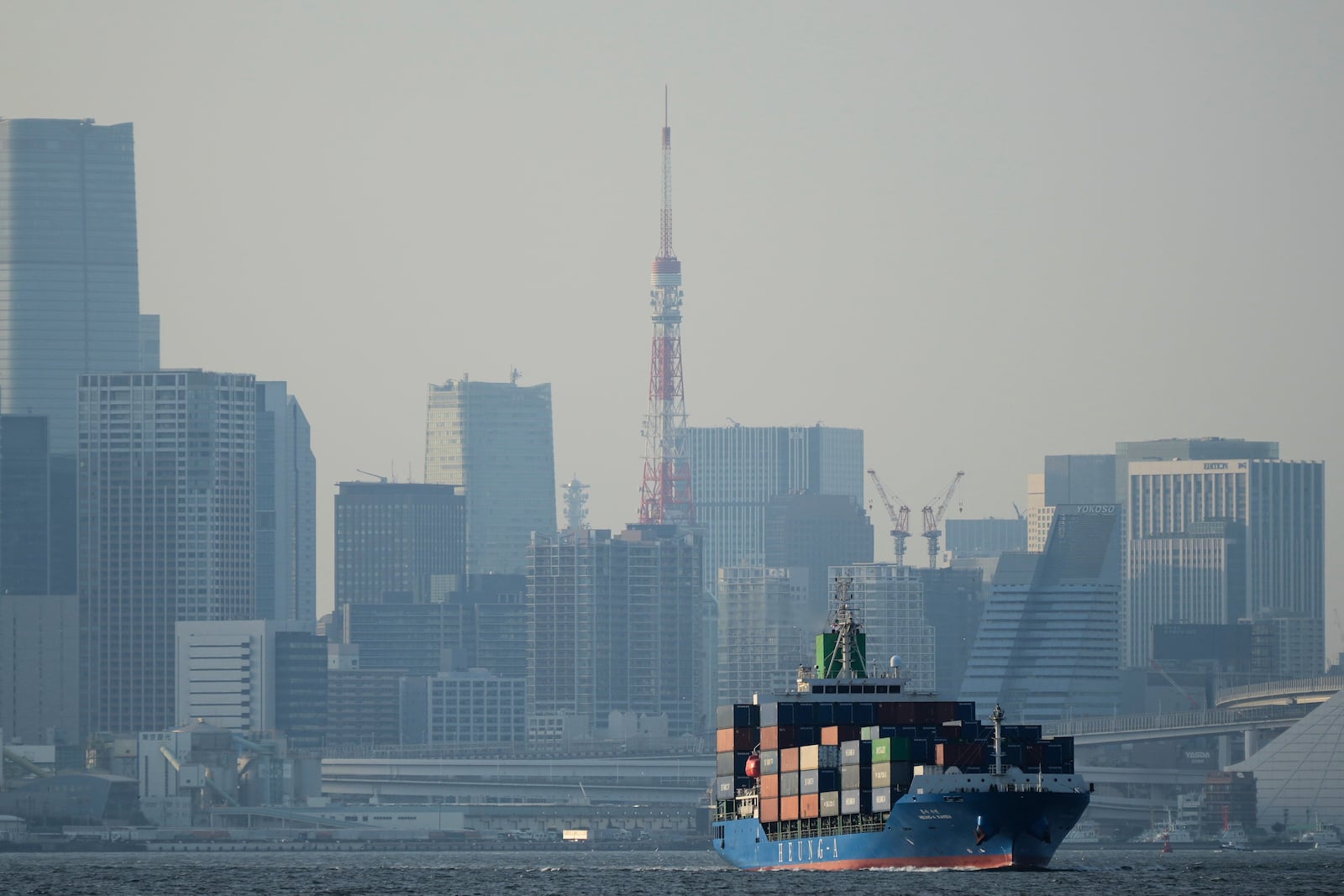 FILE - Tokyo Tower is seen amid tall buildings as a container ship leaves a cargo terminal in Tokyo, April 9, 2025. (AP Photo/Hiro Komae, File)