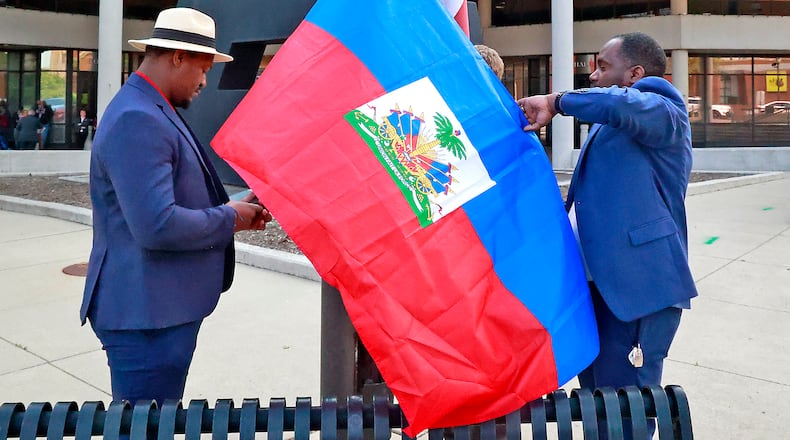 Miguelito Jerome, left, and Luckens Merzius raise the Haitian flag Thursday, May 18, 2023 in front of the Springfield City Hall. The flag raising ceremony was to mark the beginning of Flag Day in Haiti and to recognize the growing number of Haitians in the city. BILL LACKEY/STAFF