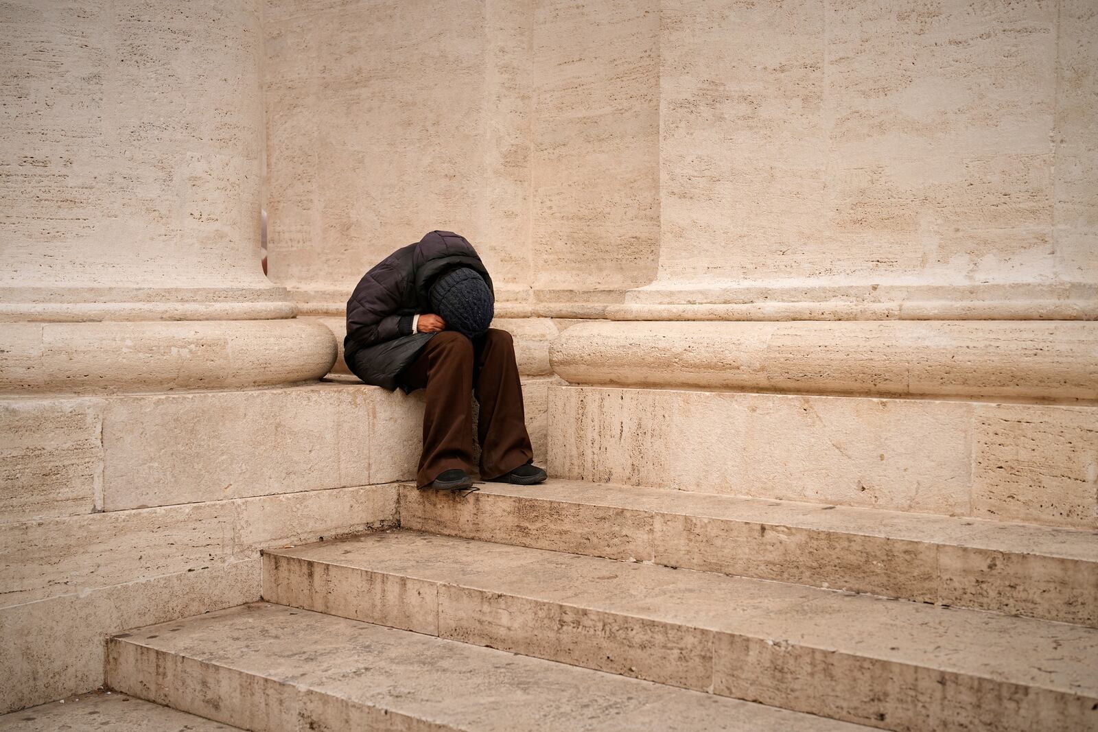 A woman sits in St. Peter's Square as people wait to pay their respects to the late Pope Francis, who will lie in state at St. Peter's Basilica for three days, at the Vatican, Wednesday, April 23, 2025. (AP Photo/Andreea Alexandru)