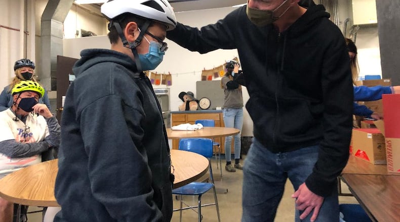 Scott King, president of Bike Greater Springfield, adjusts a new bicycling helmet for Project Jericho member Gilberto Marquez prior to a bike ride on May 6. The organizations will collaborate for a new mural on the bike path on Springfield’s south side this month. Photo by Brett Turner