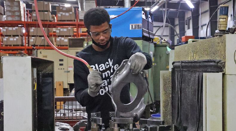A worker at Pentaflex uses compressed air to blow off a part as he takes it out of a machine Wednesday. BILL LACKEY/STAFF