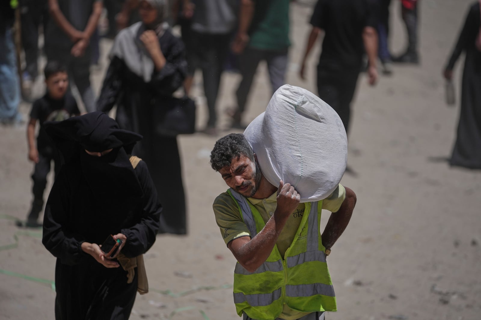 Palestinians carry bags of flour distributed by the World Food Programme (WFP) in Gaza City, northern Gaza Strip, Saturday, July 12, 2025. (AP Photo/Jehad Alshrafi)