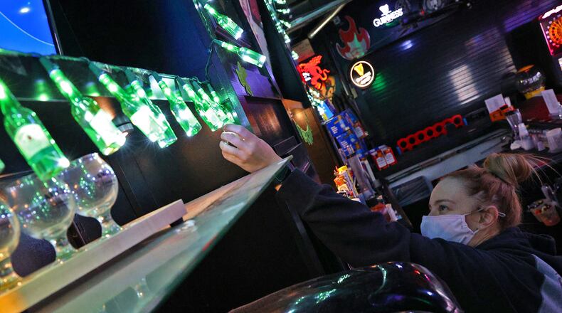 Kadie Cordle, an employee at O'Conner's Irish Pub, decorates for the St. Patrick's Day holiday Monday. BILL LACKEY/STAFF