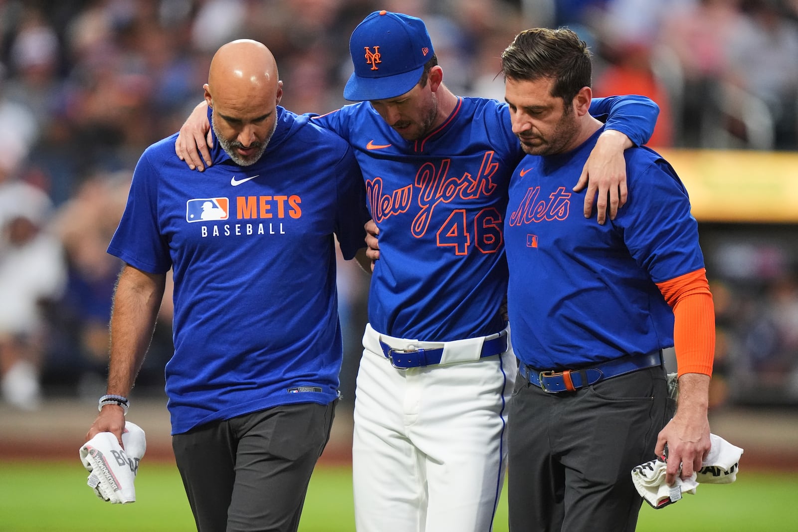New York Mets pitcher Griffin Canning is helped off the field by head athletic trainer Joseph Golia, right, and assistant athletic trainer Bryan Baca during the third inning of a baseball game against the Atlanta Braves Thursday, June 26, 2025, in New York. (AP Photo/Frank Franklin II)