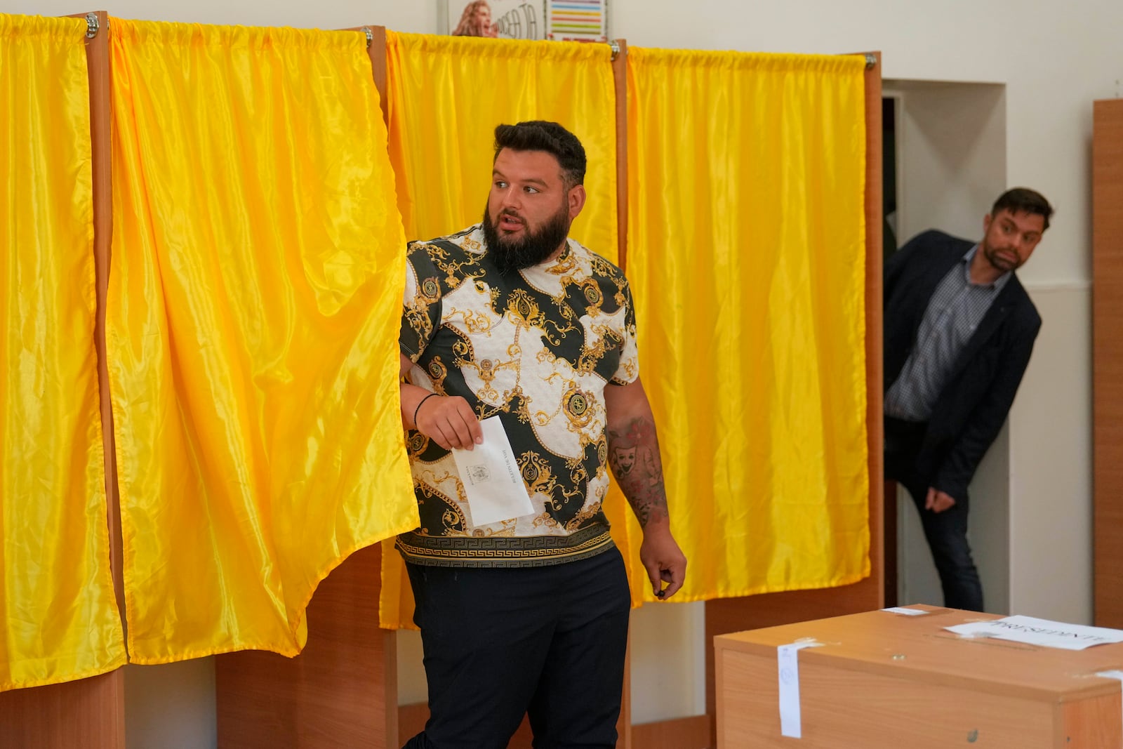 A man exits a voting booth before casting his vote in the first round of the presidential election redo in Bucharest, Romania, Sunday, May 4, 2025. (AP Photo/Vadim Ghirda)