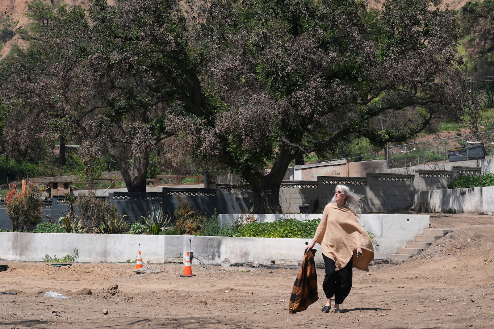 Kathryn Frazier visits her fire-damaged property, which she plans to rebuild, in Altadena, Calif., on Tuesday, April 22, 2025. (AP Photo/Damian Dovarganes)