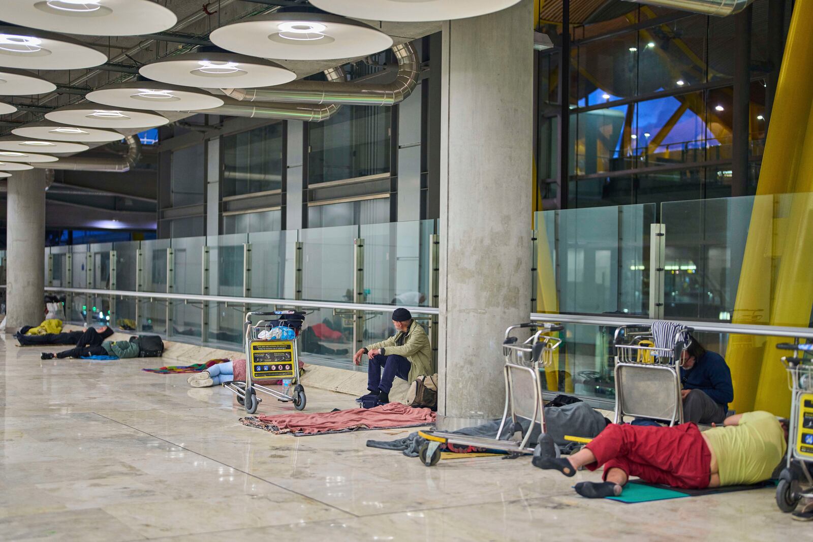 People sleep on the floor of Terminal 4 at Adolfo Suarez-Madrid Barajas Airport in Madrid, Spain, Thursday, May 15, 2025. (AP Photo/Manu Fernandez)