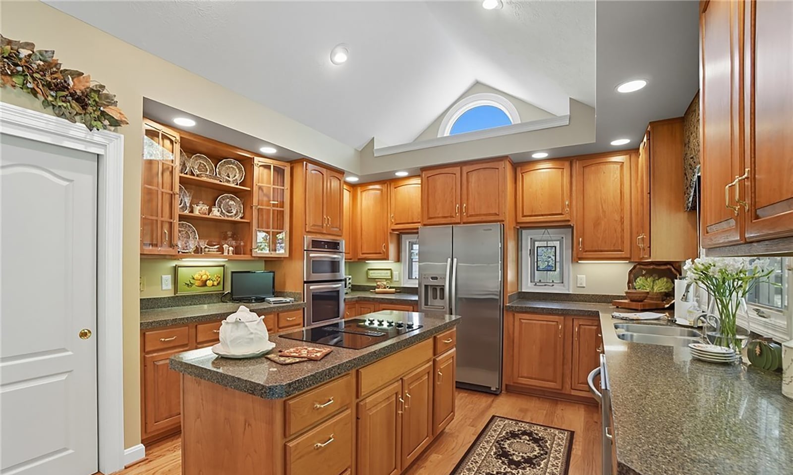 The custom kitchen features Mouser cabinets, granite countertops, wood floors and an island with a cooktop. CONTRIBUTED