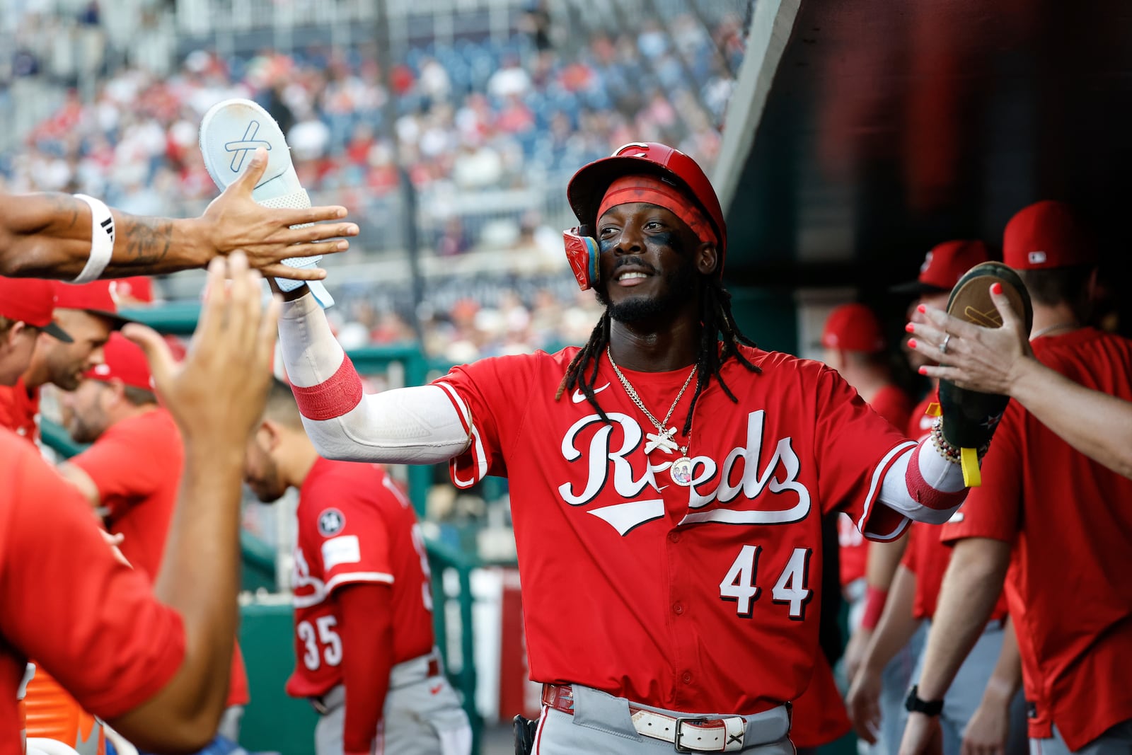 Cincinnati Reds' Elly De La Cruz (44) is greeted by teammates in the dugout after scoring on a single hit by Gavin Lux off Washington Nationals pitcher Jake Irvin during the fourth inning of a baseball game in Washington, Monday, July 21, 2025. (AP Photo/Terrance Williams)