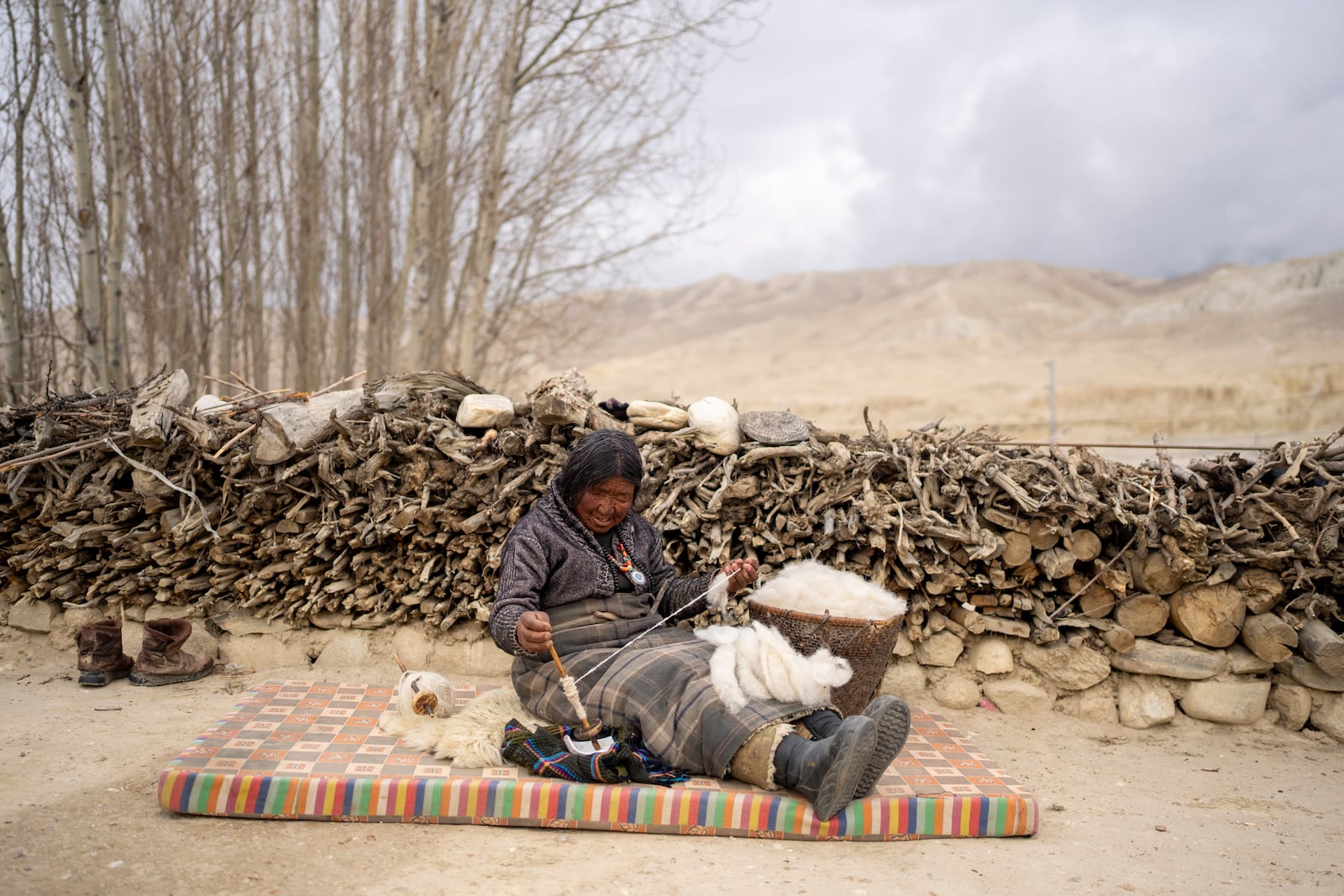 A woman makes thread from cotton at a relocated settlement of the abandoned Samjung village in the Mustang region, 462 kilometers west of Kathmandu, Nepal, Saturday, April 19, 2025. (AP Photo/Niranjan Shrestha)