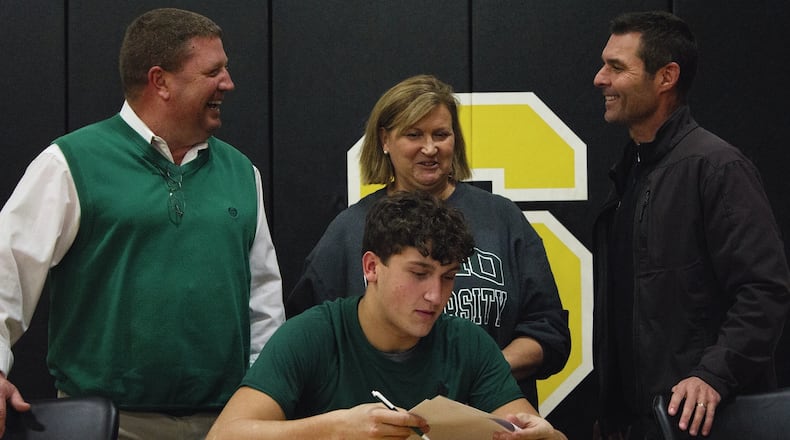 Shawnee linebacker Jack McCrory signs with Ohio University on Wednesday in the company of Braves coach Rick Meeks (left) and his parents Tony and Phyllis McCrory. JEFF GILBERT / CONTRIBUTED