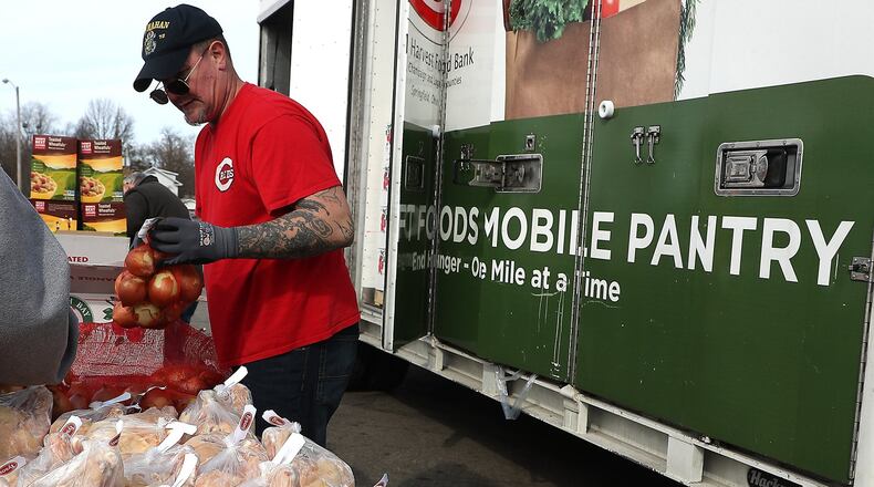 Dan Keeton puts out onions for people at the Second Harvest Food Bank’s Mobile Food Pantry in the parking lot on the former Kroger on South Limestone Street. BILL LACKEY/STAFF