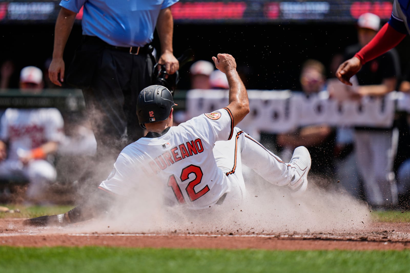 Baltimore Orioles' Ramon Laureano (12) slides into home plate to score on a sacrifice fly hit by Ramon Urias during the first inning in the first baseball game of a doubleheader against the Toronto Blue Jays, Tuesday, July 29, 2025, in Baltimore. (AP Photo/Stephanie Scarbrough)
