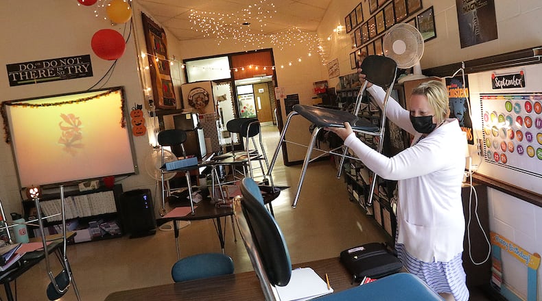 Clark and Champaign county school district coronavirus cases have dropped by over 50. Here, Sarah Covac takes the chairs off the desks in her 5th grade classroom at South Vienna Middle School. BILL LACKEY/STAFF