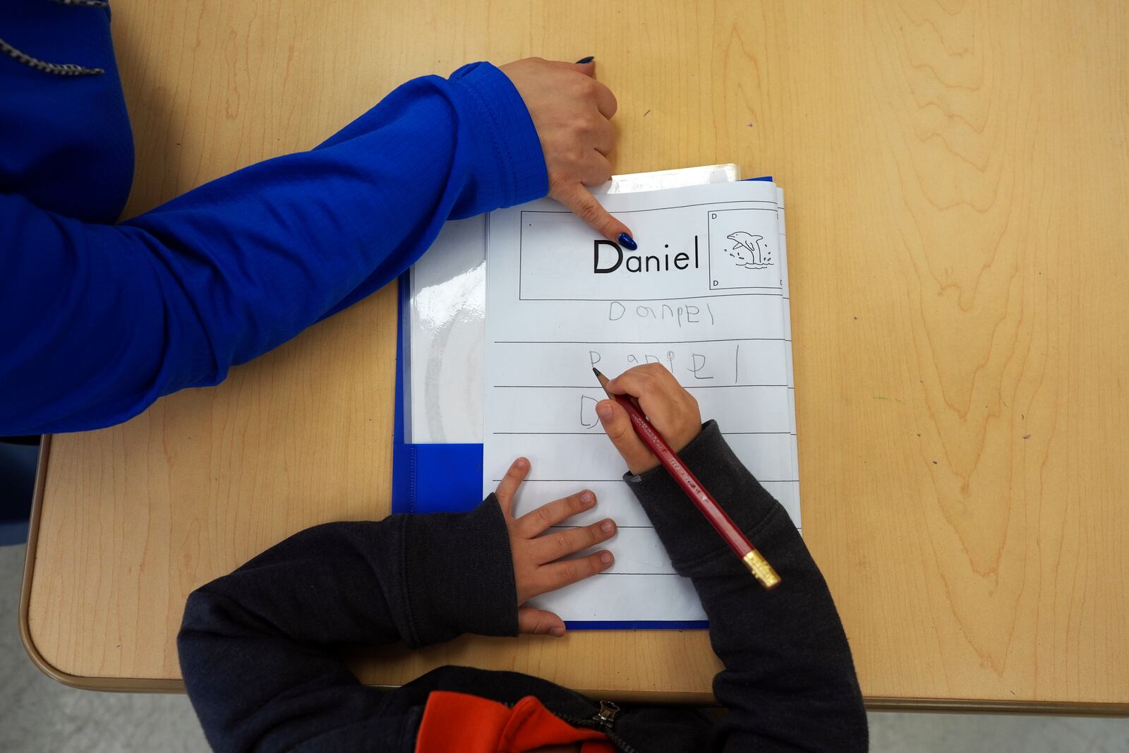 FILE - Easterseals Head Start program teaching assistant Tania Ortiz helps a student practice writing his name, Jan. 29, 2025, in Miami. (AP Photo/Rebecca Blackwell, File)