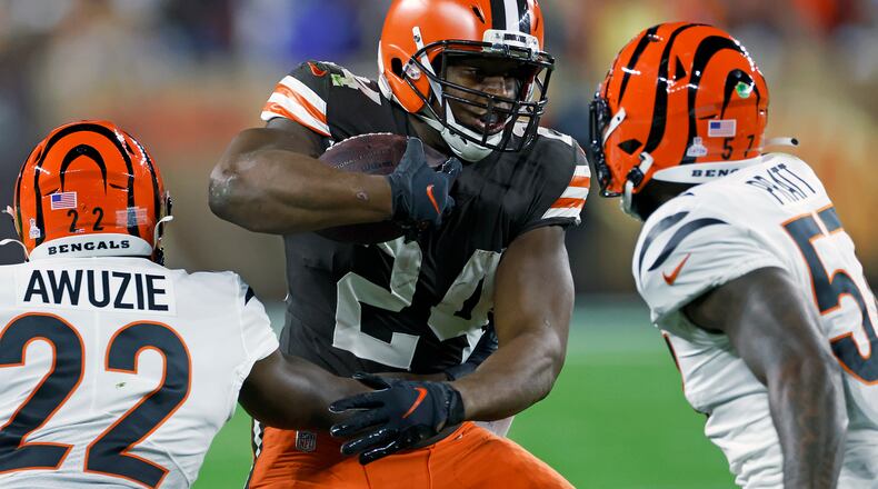 Cleveland Browns running back Nick Chubb (24) carries the ball with Cincinnati Bengals cornerback Chidobe Awuzie (22) and linebacker Germaine Pratt (57) defending during the first half of an NFL football game in Cleveland, Monday, Oct. 31, 2022. (AP Photo/Ron Schwane)